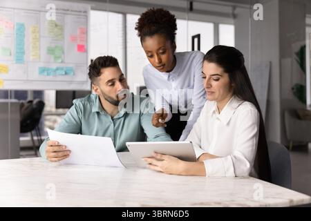 Colleagues working on joint project using digital and print resources Stock Photo