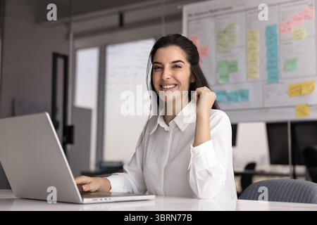 Portrait of smiling attractive Latina female manager working using laptop Stock Photo