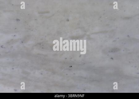 Close-up of mottled white and gray marble with subtle veining and small dark inclusions. Stock Photo