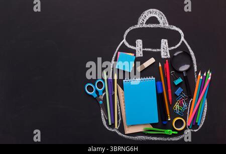 Chalk painted backpack with office supplies on black background Stock Photo