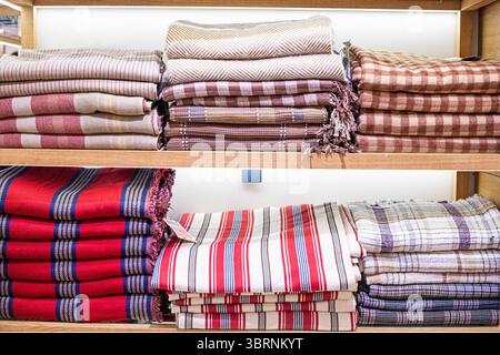 checkered scarves and blankets stacked on wooden shelves Stock Photo