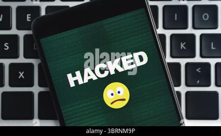 Smartphone with hacked inscription and sad emoji icon on screen Stock Photo