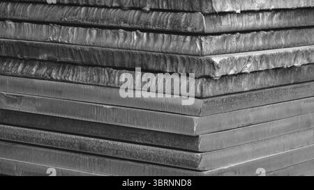 Stack of black thick heavy metal plates rusty uneven surface after laser cutting. plates stacked top each other, creating sense depth and texture. sce Stock Photo