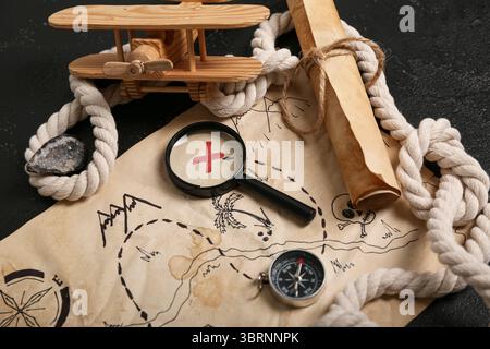 Treasure map with travel equipment, toy airplane and golden nuggets on black background Stock Photo
