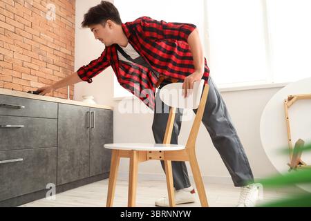 Male worker assembling chair in kitchen Stock Photo
