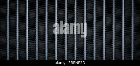 Close-up of a black and silver metallic object with many fine lines. object is a radiator as a black textured background blue tone Stock Photo
