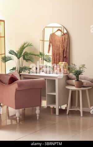 Interior of dressing room with table, makeup products and armchair Stock Photo