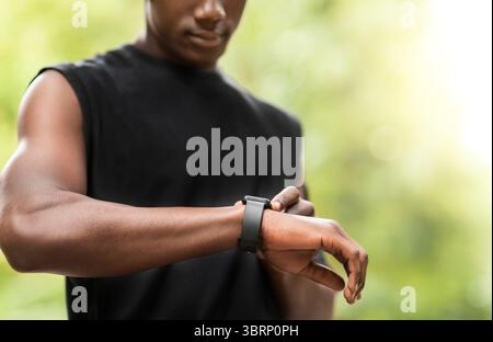 Cropped of black sportsman using his smartwatch Stock Photo