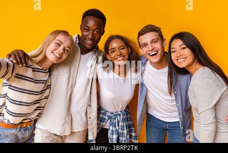 Friendly international students taking selfie over yellow background Stock Photo