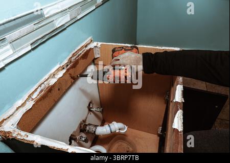 Handyman replacing an old bathroom cabinet. Plumbing repair service, assembling and install concept. Stock Photo