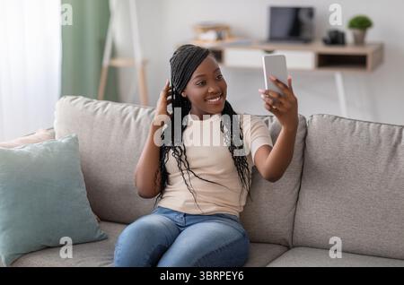 Cute young black lady taking selfie on smartphone Stock Photo