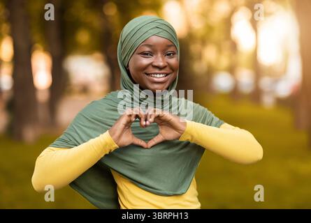 Love Concept. Smiling African Muslim Woman In Hijab Showing Heart Gesture Stock Photo