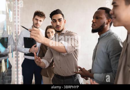 Businesspeople having meeting using sticky notes on glass wall Stock Photo