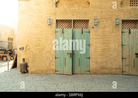 aged teal wooden door with iron lock and handle detail on a lime plastered old wall background, Heritage town street view Stock Photo