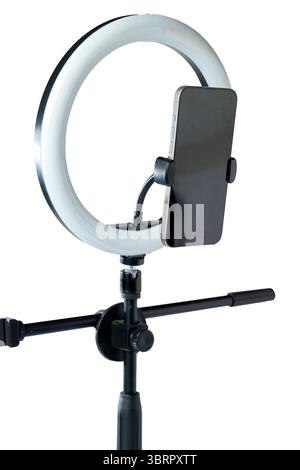 Round LED ring light with a cellphone on a phone holder isolated over a white background. Vlogging or live streaming equipment. Mockup or Copy space Stock Photo