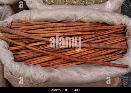 A large, burlap sack containing long strips of cinnamon stick, a spice made from the bark of the cinnamon tree. Stock Photo