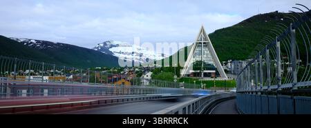 A long exposure captures the Arctic Cathedral framed by dynamic light trails and snow-capped mountains in Tromsø, Norway Stock Photo