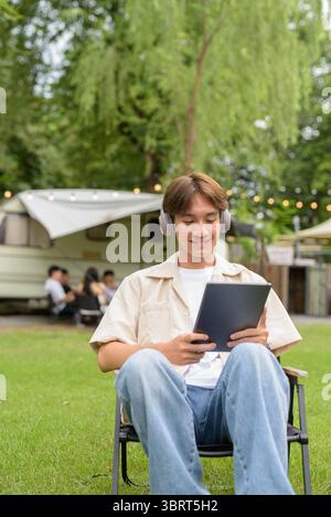 Young Asian non binary person having road trip and camping with friends in nature Stock Photo
