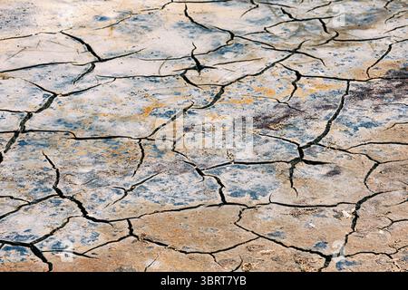 Dry cracked soil creating a colorful and textured background, symbolizing drought, climate change, and environmental challenges Stock Photo