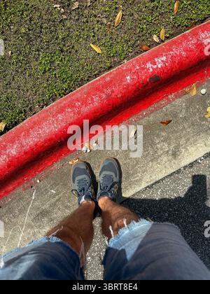 27 May 2025 - Austin, TX, USA - The Red painted curbs of a No Parking Tow away zone on a freeway, in bright sunshine. Stock Photo