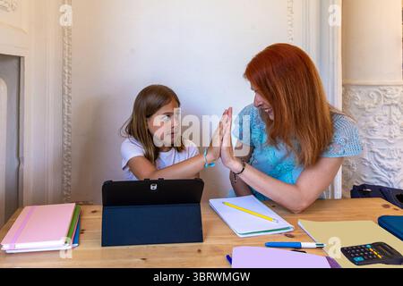 Mother and daughter giving high five while doing homework together Stock Photo
