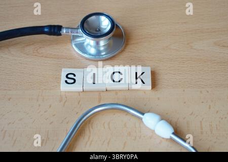 Conceptual image representing illness, with the word “sick” in wooden letters alongside a stethoscope symbolizing medical care. Stock Photo