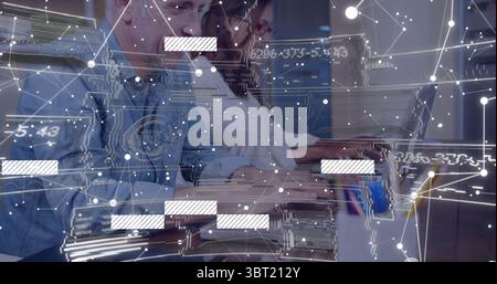 Coworkers wearing casual business attire analyzing data on laptop in office with network overlay Stock Photo