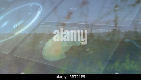 Displaying radar chart graphic overlaying solar panels in grass, with grid overlays and tree line Stock Photo