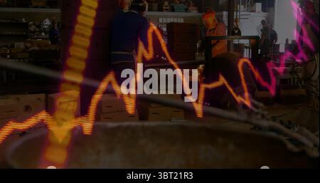 Three male technicians in coveralls and hard hats checking machine in workshop, with data overlay Stock Photo
