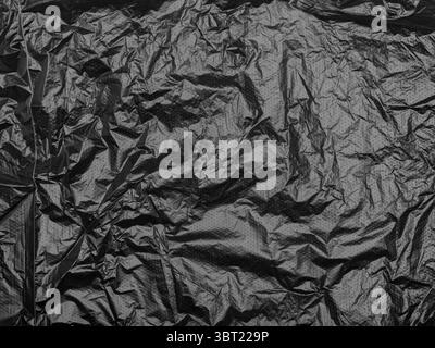 Crumpled black plastic sheet with a subtle dotted texture. Stock Photo