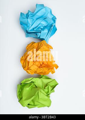 Three crumpled balls of brightly colored paper, blue, orange, and green, on white background. Stock Photo