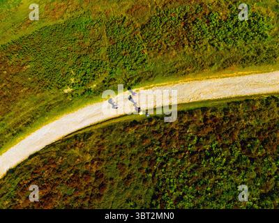 From a high angle, a group of four people are walking along a dirt path through a grassy area towards the peak of Moel Famau in the Clwydian Range, No Stock Photo