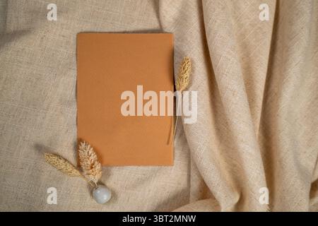Minimal brown paper card mockup with dried grass on beige linen fabric background Stock Photo