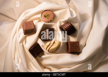 Indulge in an exquisite assortment of gourmet chocolates, artfully displayed on luxurious fabric. Perfect for confectionery branding, sweet treats. Stock Photo