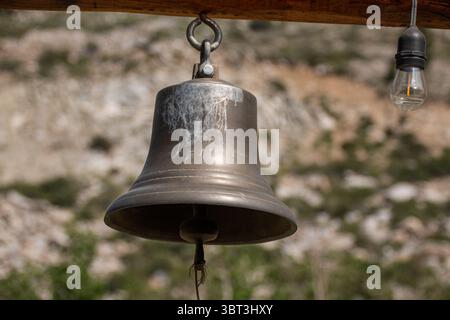 Dinner Bell 2. A metal bell hangs from a wood beam. Stock Photo