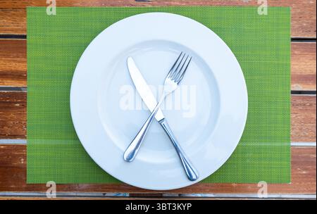 white ceramic plate with fork and knife on a jute placemat Stock Photo