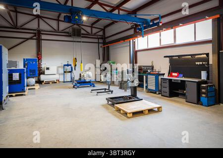Wide view of an industrial workshop showing an overhead crane, workbenches, and various equipment used for maintenance and repair Stock Photo