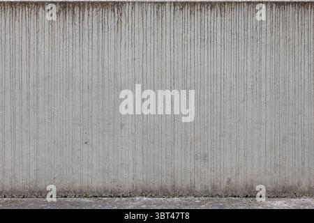 Water marks on a concrete wall exterior. Traces of dirty rain water in vertical direction. Weathered building exterior close-up. Abstract background. Stock Photo