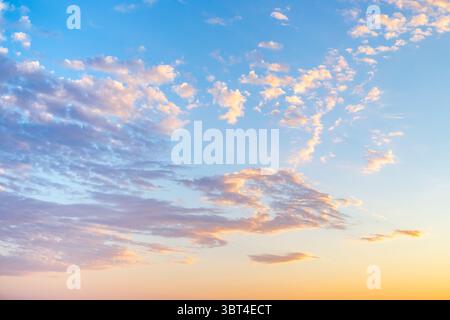 sunrise with light cirrus clouds in soft orange and pink tones, with the sun on the horizon. Stock Photo