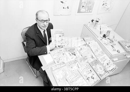 Artist Mr. Piet Persons Drawings, Whizgle News, Dutch Desk, The Netherlands, 1950 - 2000 on 27-02-1970. The image shows these topics. The scene features an older man seated at a small table, which is cluttered with a collection of comic books, all prominently arranged. He is dressed in a formal suit, lending a contrast to the playful nature of the comics around him. His expression is serious and focused as he holds one comic book, displaying it towards the viewer. The comics are brightly colored, with vivid illustrations on their covers, showcasing dynamic characters and action. The table itse Stock Photo