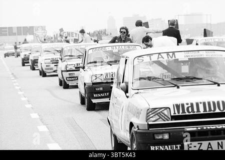 Renault race Zandvoort Renault Zandvoort, Whizgle News, Dutch Desk, The Netherlands, 1950 - 2000 on 07-04-1980. The image contains these topics. The scene captures a moment in a motorsport event, with several compact cars lined up on an asphalt track, their bumpers facing the viewer. Each car exhibits a sleek, aerodynamic design, the bodywork painted in varying shades of white and light colors, contributing to a uniform yet lively atmosphere. The vehicles have distinctive numbers and names displayed on their hoods, hinting at rivalry and competition. The cars stand in a neat formation, suggest Stock Photo