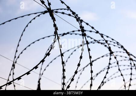 Barbed wire on sky background. Concept of boundary, prison, war or military base Stock Photo