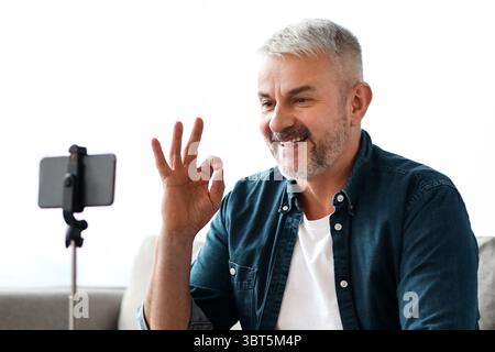 Smiling senior man vlogger broadcasting from home Stock Photo