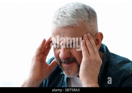 Closeup of mature grey-haired man suffering from headache Stock Photo