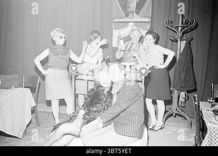 Irma La Douce Beverwijk Theater, Whizgle News, Dutch Desk, The Netherlands, 1950 - 2000 on 02-03-1968. The image includes these topics. In a lively scene capturing a moment of celebration, a group of stylishly dressed individuals occupies a dimly lit venue. The background features rich, dark curtains that create an intimate atmosphere. In the foreground, a couple poses together on a plush seat. The woman, adorned with a glamorous feather boa, exudes confidence and charm, while the man beside her, dressed in a pinstriped suit, leans in, their expressions suggesting joy and flirtation. Stock Photo
