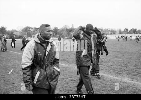 Football RCH - WSV, Whizgle News, Dutch Desk, The Netherlands, 1950 - 2000 on 11-05-1996. These topics appear in the image. In a grassy setting, two individuals walk along a well-worn path that cuts through the field. The atmosphere feels tense yet determined, hinting at a recent competitive event. The first person, dressed in a dark jacket with a hood pulled back, exhibits a thoughtful expression as they glance toward the ground. Their attire, primarily dark with hints of beige, suggests practicality and readiness. The second individual, slightly taller, has a lighter jacket, primarily grey, Stock Photo