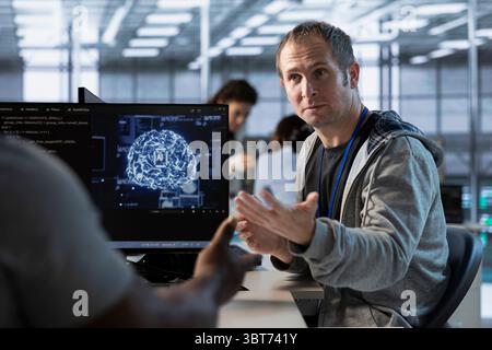Team of admins using artificial intelligence technology to optimize data center workplace. Coworkers doing brainstorming in server hub, using AI tech to streamline operations and accurately forecast issues Stock Photo