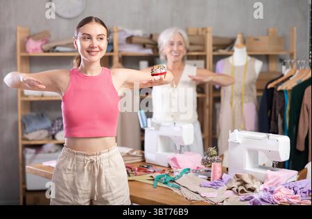 Elderly and adult women doing warm-up exercises in sewing workshop Stock Photo