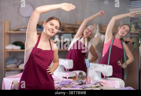 team of dressmakers doing a warm-up in the workshop Stock Photo