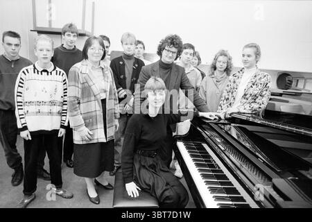 Martijn and Mieke van de Hoek piano study day in Egelantier Music, Whizgle News, Dutch Desk, The Netherlands, 1950 - 2000 on 17-02-1988. The image shows these topics. In a spacious, well-lit room, a group of individuals is gathered around a grand piano, which is positioned prominently in the foreground. The piano's glossy black surface reflects the light, creating a striking contrast with the muted colors surrounding it. In front of the piano sits a woman, her hand resting lightly on the instrument. She is dressed in a black top and appears confident, with a warm smile that suggests she is cen Stock Photo